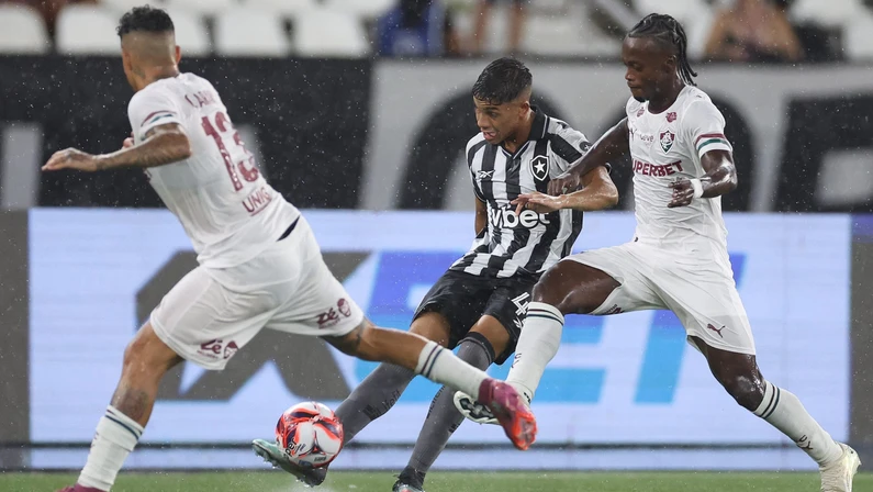 Jogadores de Botafogo e Fluminense disputam bola no gramado molhado do Estádio Nilton Santos durante clássico do Campeonato Carioca
