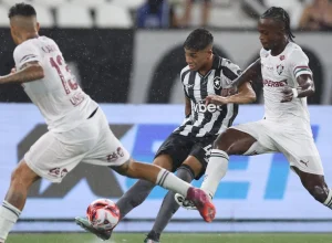Jogadores de Botafogo e Fluminense disputam bola no gramado molhado do Estádio Nilton Santos durante clássico do Campeonato Carioca